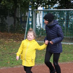 Ein Kind läuft zusammen mit einer Erwachsenen Person. Das Kind hält die Hand der Person.