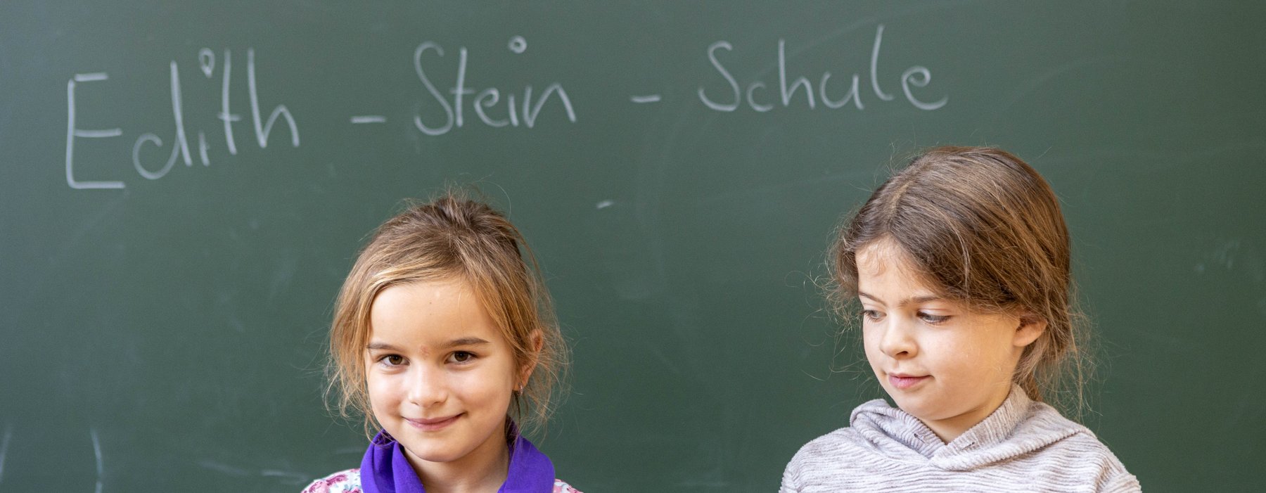Zwei Kinder Stehen vor einer Tafel auf der Edith - Stein - Schule steht