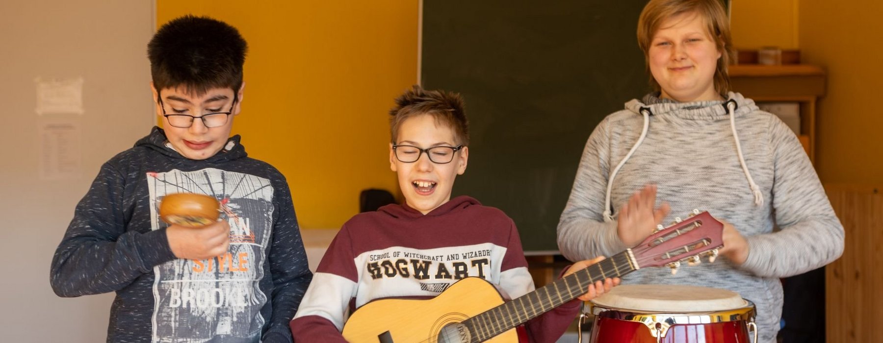 Drei Kinder musizieren auf verschiedenen Instrumenten