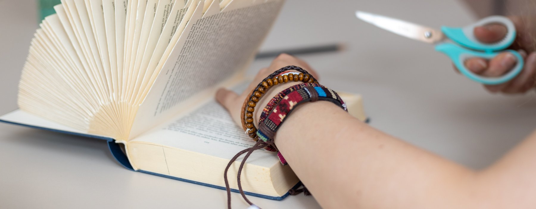 Hier wird mit einer Schere gezielt bestimmte stellen in einer Buch Seite eingeschnitten um daraus Kunst zu machen.